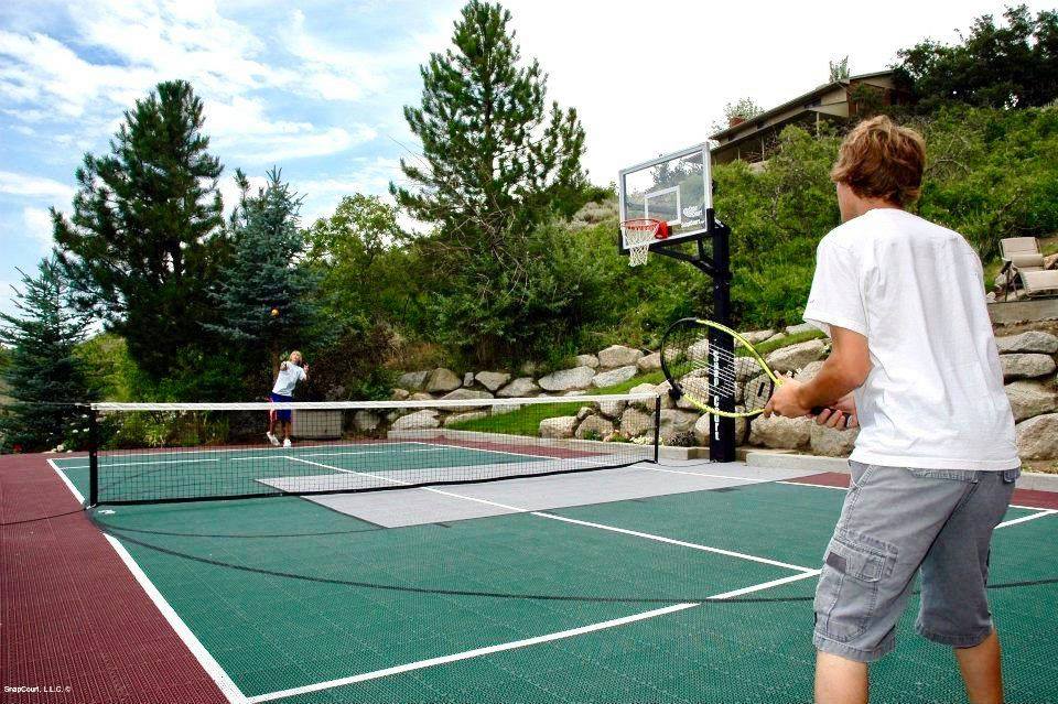 A boy is playing a game of tennis on a residential court.