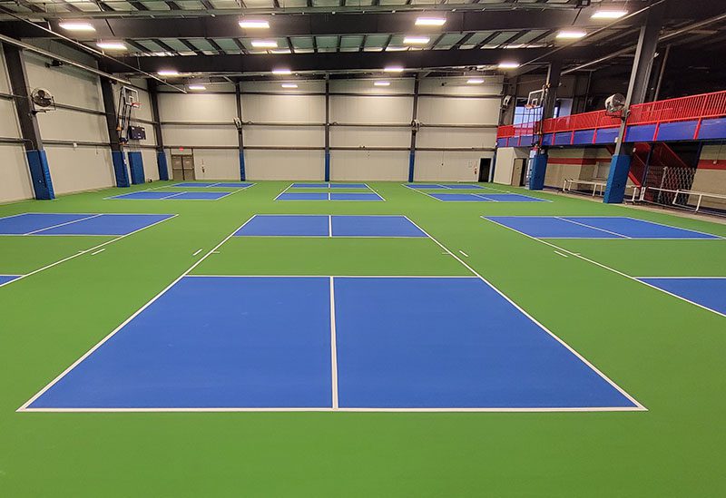 A large indoor tennis court with blue and blue tennis courts.