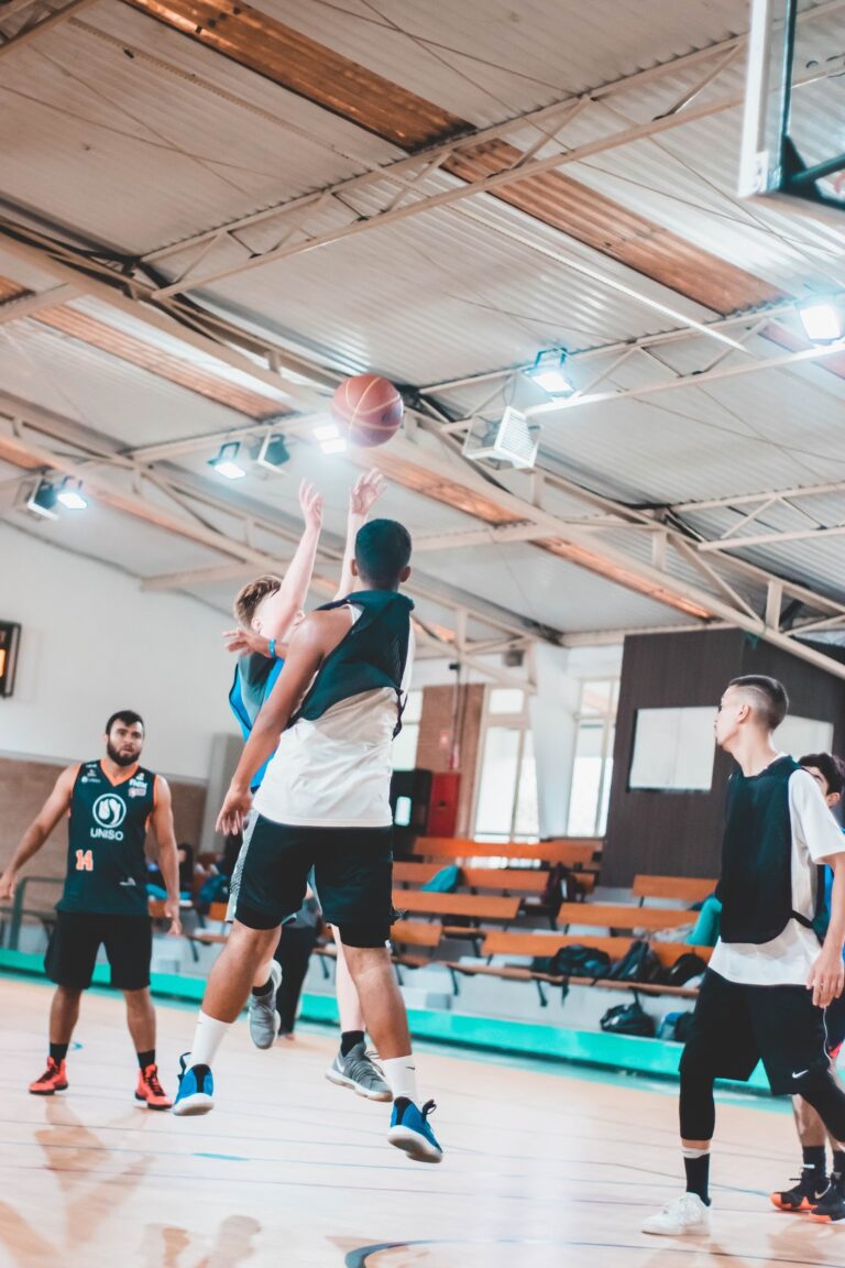 A group playing basketball in a gym for maintaining an indoor basketball court.