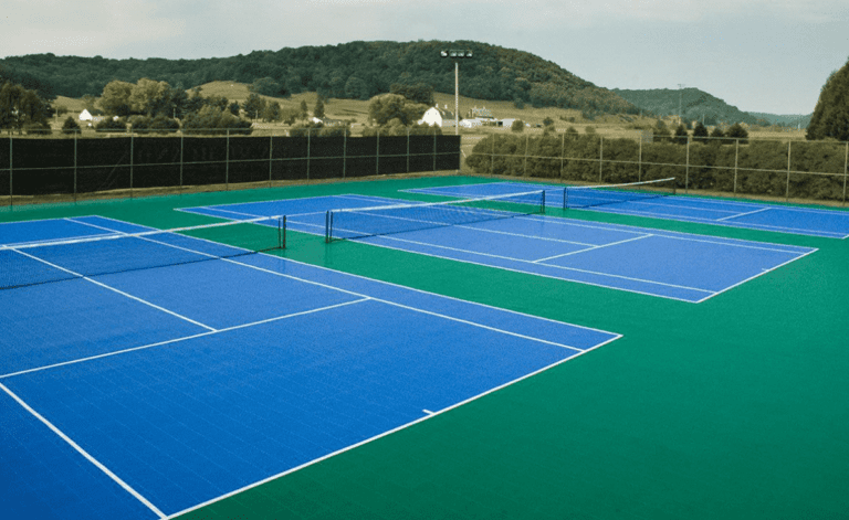 A tennis court with blue and white lines that may require resurfacing.