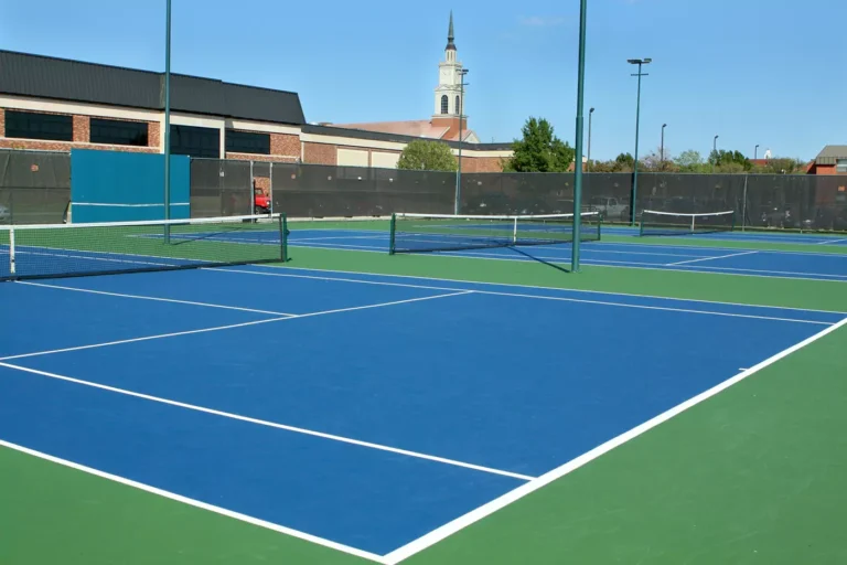 A tennis court with a net overlooking a building in the background.